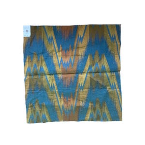 May include: A blue, brown, and gold fabric with a chevron pattern. The fabric is woven and has a textured surface.