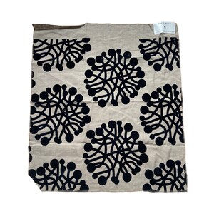 May include: Beige fabric with a black repeating pattern of stylized flowers. The fabric has a slightly textured surface.