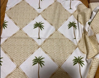 May include: White fabric with a repeating pattern of brown woven squares and green palm trees. The fabric is folded in the top right corner.