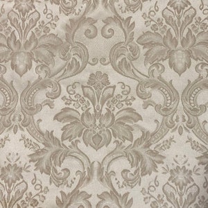 May include: A beige fabric with a brown damask pattern. The pattern features intricate floral and scroll designs.