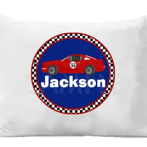 May include: White pillow with a red race car on a blue circle with a black and white checkered border. The text "Jackson" is below the car.