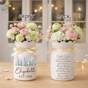 May include: Two white ceramic vases with scalloped rims and cream ribbons. The front vase features a blue floral print, the name Elizabeth, and EST. 1966. The back vase displays the text Chapter Sixty, followed by a sentimental birthday message.