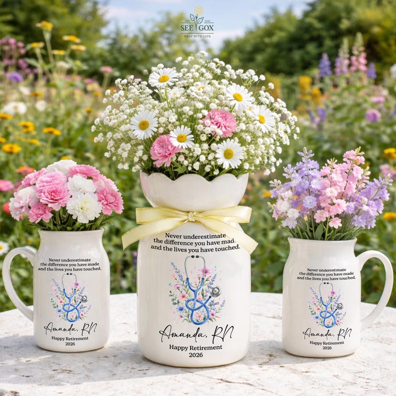 May include: Three white ceramic vessels featuring a floral stethoscope graphic and the text: Never underestimate the difference you have made, and the lives you have touched. Amanda, RN. Happy Retirement 2026. The vessels contain bouquets of flowers.