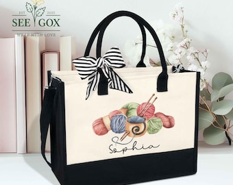 May include: A black and cream tote bag with black handles and a striped bow. The bag features a watercolor illustration of yarn balls, knitting needles, and a cup. The name "Sophia" is written below the illustration.