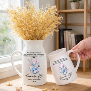 May include: A white ceramic pitcher and a matching mug, both featuring a blue stethoscope graphic surrounded by colorful flowers. The text reads: Never underestimate the difference you have made and the lives you have touched. Amanda, RN. Happy Retirement 2026.