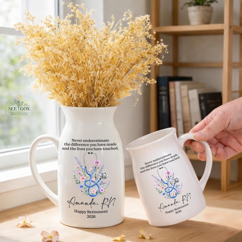 May include: A white ceramic pitcher and a matching mug, both featuring a blue stethoscope graphic surrounded by colorful flowers. The text reads: Never underestimate the difference you have made and the lives you have touched. Amanda, RN. Happy Retirement 2026.