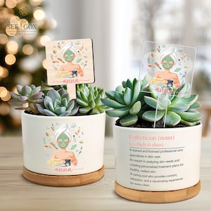 May include: Two succulent plants in white ceramic pots with bamboo saucers. Each pot has a decorative sign with a spa-themed illustration and the name "Anna." One pot has the definition of "Esthetician."