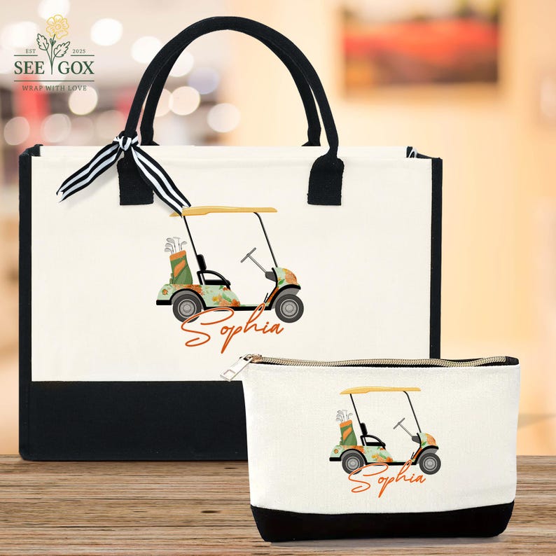 Puede incluir: Un bolso tote blanco y un neceser a juego con base y asas negras. Ambas bolsas presentan un dise&ntilde;o de carrito de golf con el nombre "Sophia" en escritura naranja. El bolso tote tiene una cinta a rayas blancas y negras atada al asa.