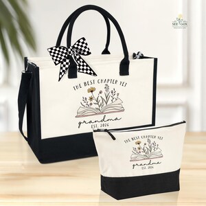May include: A tote bag and matching cosmetic bag set. The bags are primarily off-white with black accents and handles. The tote bag has a black and white checkered bow. Both bags feature the text "THE BEST CHAPTER YET grandma EST. 2026" with floral illustrations.