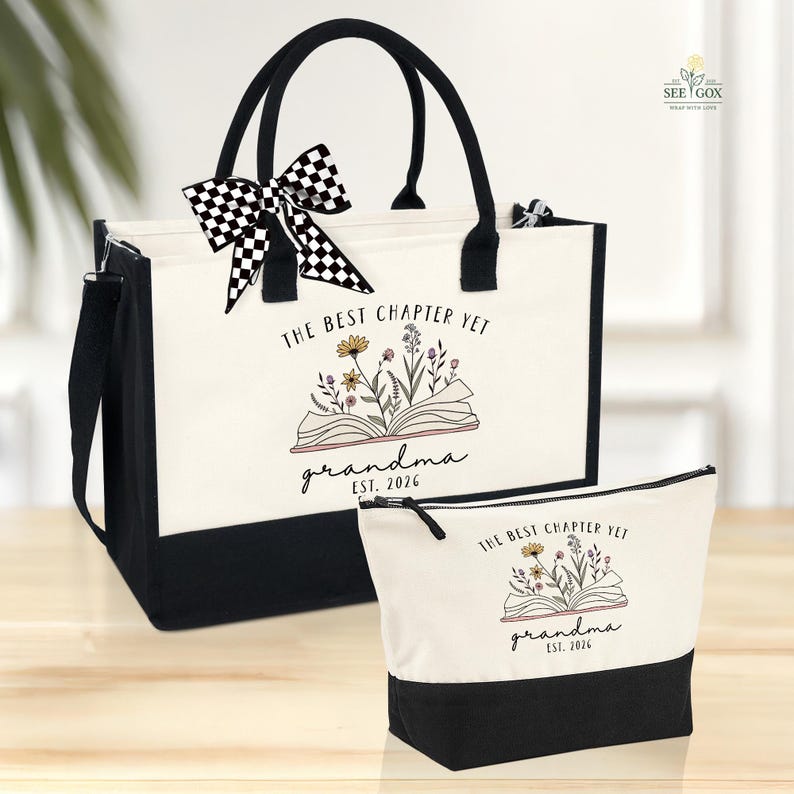 May include: A tote bag and matching cosmetic bag set. The bags are primarily off-white with black accents and handles. The tote bag has a black and white checkered bow. Both bags feature the text "THE BEST CHAPTER YET grandma EST. 2026" with floral illustrations.