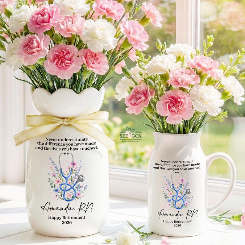 May include: A white ceramic vase and a matching white ceramic mug, both filled with pink and white carnations. Each item features a blue stethoscope graphic, floral accents, and the text: Never underestimate the difference you have made and the lives you have touched. Amanda, RN. Happy Retirement 2026.