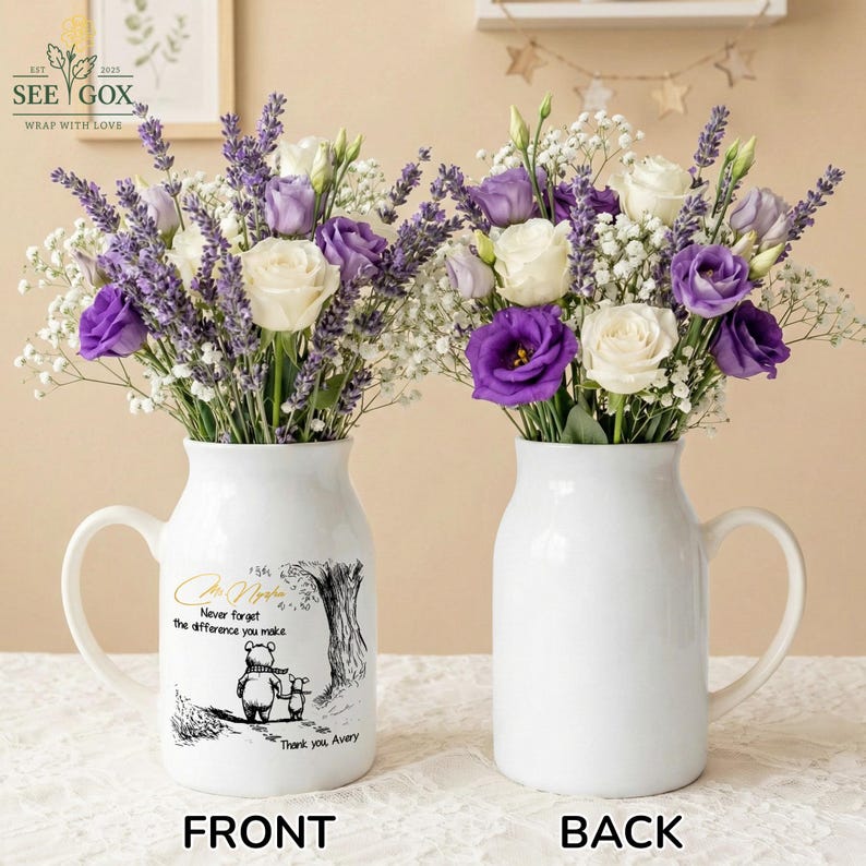 May include: Two white ceramic vases with handles, each filled with a bouquet of white, purple, and lavender flowers. One vase has a Winnie the Pooh illustration and text that reads "Never forget the difference you make."