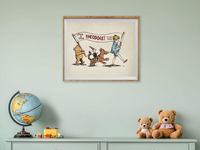 May include: A framed print featuring Winnie the Pooh characters. The illustration shows Pooh, Piglet, and Tigger carrying a banner that reads "THEODORE!" with the date and weight. The artwork is in a wooden frame and is displayed on a light green wall.