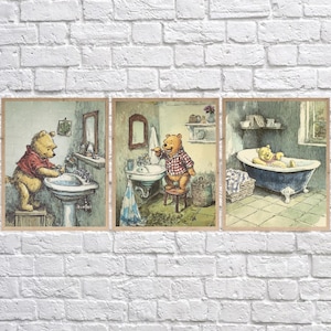 May include: Set of three framed prints featuring Winnie the Pooh in a bathroom setting. One shows Pooh washing his hands, another brushing his teeth, and the last relaxing in a bathtub. The artwork has a vintage, watercolor style.