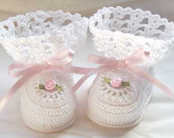 May include: A pair of white crochet baby booties with pink satin ribbon bows and small pink rose embellishments. The booties have a delicate, lacy trim around the top.