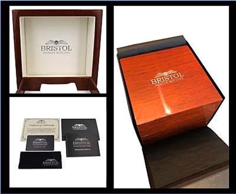 May include: A wooden watch box with a glossy, reddish-brown finish. The box is open, revealing a cream-colored interior with the "BRISTOL AVIATOR WATCHES" logo. Additional items include a certificate, cards, and a black cloth.