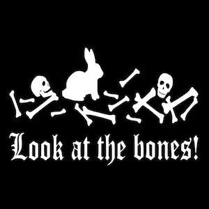 Peut inclure: Graphique noir avec des illustrations blanches d'un lapin, de crânes et d'os. Le texte "Look at the bones!" est écrit en police gothique sous les illustrations.