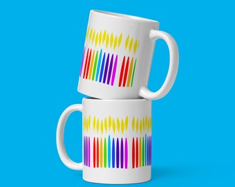 May include: Two white ceramic mugs stacked on top of each other. Both mugs feature a colorful rainbow design of candles with yellow flames.