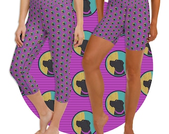 May include: Two women wearing leggings and shorts with a black Labrador Retriever print on a pink and teal striped background. The leggings are cropped and the shorts are short. The print is repeated throughout the fabric.