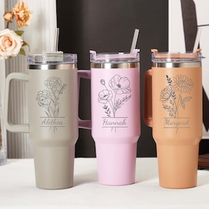 May include: Three insulated tumblers in beige, pink, and peach, each with a handle, straw, and floral engraving. The beige tumbler has the name "Alethea", the pink one "Hannah", and the peach one "Margaret".