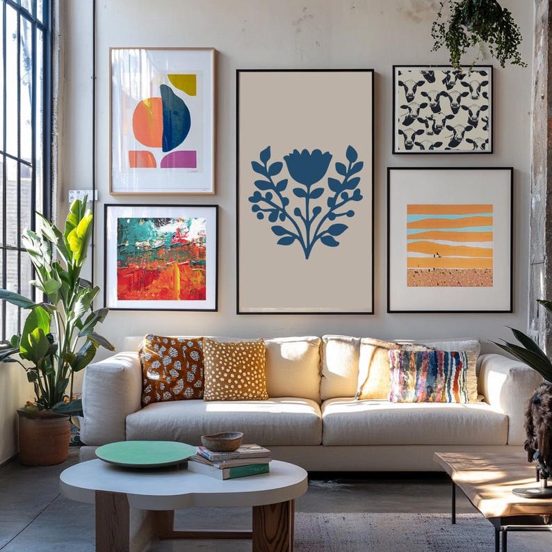 May include: A living room scene featuring a white sofa with decorative pillows and a round coffee table. Above the sofa, framed abstract art pieces in various colors and styles are displayed, creating a gallery wall aesthetic.