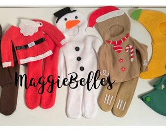 Puede incluir: Un conjunto de seis trajes de elfo navideño de fieltro, que incluyen un reno, un Papá Noel, un muñeco de nieve, un hombre de jengibre, una luna creciente y un árbol de Navidad. Los trajes están hechos a mano y presentan varios detalles festivos.