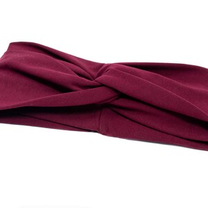 May include: A burgundy fabric headband with a twisted knot design.