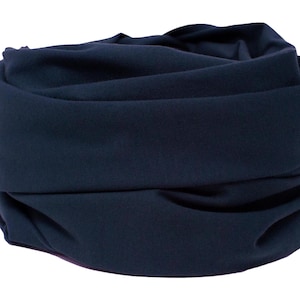 Pode incluir: Um cachecol de pescoço de tecido azul escuro, dobrado e enrolado em forma de tubo.