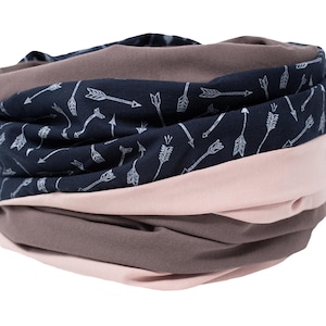 Op de afbeelding: Een meerlagige infinity sjaal in marine, roze en bruin. De marineblauwe laag heeft een wit pijlenpatroon. De sjaal is gemaakt van zachte stof en is ontworpen om om de nek te worden gedragen.