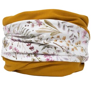 May include: Mustard yellow and floral print neck warmer. The neck warmer has a mustard yellow base with a white floral print band. The floral print includes pink, brown, and green leaves and flowers.