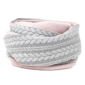 May include: A gray and pink reversible neck warmer with a cable knit pattern. The warmer is made of soft fleece and is perfect for keeping warm in the winter.