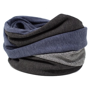 Puede incluir: Una bufanda infinita azul y negra con un patrón de espiga. La bufanda está hecha de una tela suave y cómoda y es perfecta para mantenerse caliente en invierno.