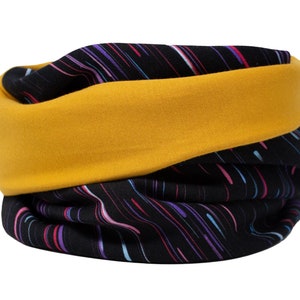 Puede incluir: Un pasamontañas negro y amarillo con un patrón abstracto colorido. El pasamontañas está hecho de un tejido suave y elástico y se puede usar como bufanda, diadema o mascarilla.