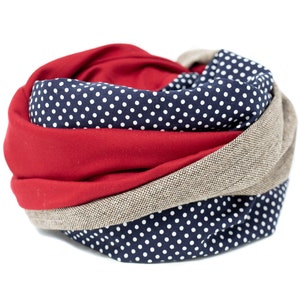 May include: A red, beige, and navy blue infinity scarf with a white polka dot pattern.