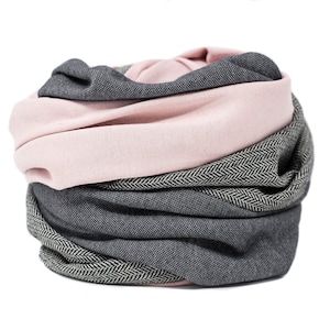 May include: A pink and gray infinity scarf with a herringbone pattern. The scarf is folded and rolled into a circle.