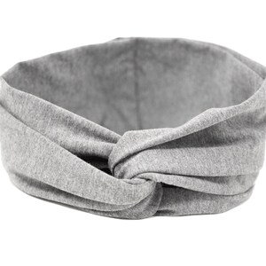 Könnte beinhalten: Ein graues Stoff Stirnband mit einem Knotendesign. Das Stirnband ist aus weichem, dehnbarem Material und perfekt, um Haare aus dem Gesicht zu halten.