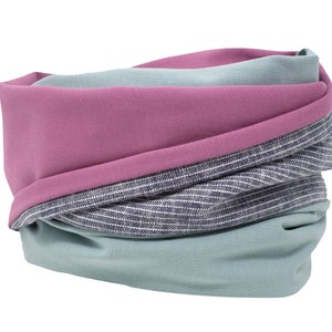 Könnte beinhalten: Ein mehrfarbiger Halsschmeichler mit einem pinkfarbenen, blauen und weißen Streifenmuster. Der Halsschmeichler ist aus einem weichen, bequemen Stoff gefertigt und perfekt, um sich im Winter warm zu halten.