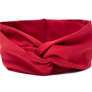 May include: A red fabric headband with a knotted design. The headband is made of a soft, stretchy material and is perfect for keeping hair out of your face.