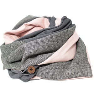 Può includere: Una sciarpa infinita grigia e rosa con un motivo a spina di pesce e un bottone in legno.