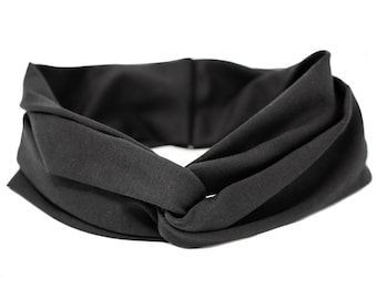 Puede incluir: Una diadema de tela negra con un diseño de nudo retorcido. La diadema está hecha de un material suave y elástico, ideal para mantener el cabello fuera de la cara.