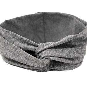 May include: A gray fabric headband with a knotted design. The headband is made of a soft, stretchy material.