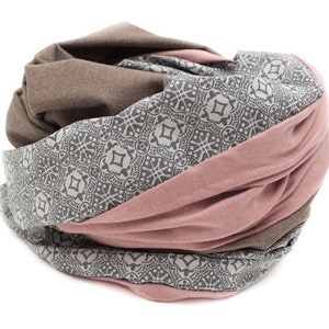 May include: A brown, pink, and gray patterned infinity scarf. The scarf is made of soft fabric and is perfect for adding a touch of style to any outfit.