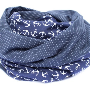 May include: A navy blue scarf with a white anchor pattern on one side and a white polka dot pattern on the other side.
