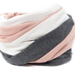 May include: A soft, cozy scarf in a striped pattern of pink, white, and gray.