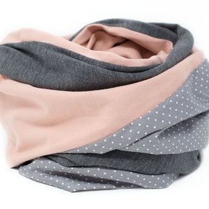May include: A gray and pink infinity scarf with white polka dots. The scarf is made of a soft, stretchy fabric and is perfect for keeping warm in the winter.