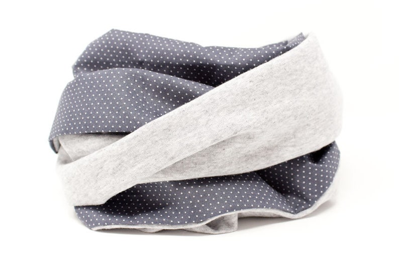 Puede incluir: Un calentador de cuello de tela gris y gris oscuro con un patr&oacute;n de lunares blancos.