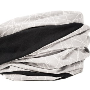 May include: A gray and black neck gaiter with a geometric pattern. The gaiter is made of a soft, stretchy fabric and can be worn in a variety of ways.