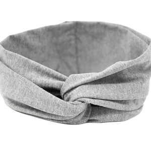 May include: Gray fabric headband with a knotted design. The headband is made of a soft, stretchy material and is perfect for keeping hair out of your face.
