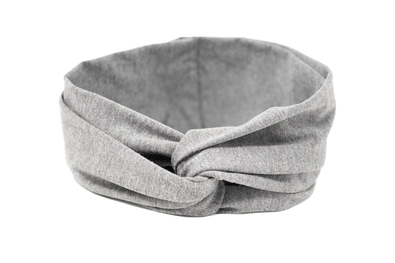 May include: Gray fabric headband with a knotted design. The headband is made of a soft, stretchy material.