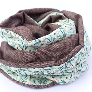 Peut inclure: Une &eacute;charpe infinie marron et blanche avec un motif floral. L'&eacute;charpe est faite d'un tissu doux et textur&eacute;.